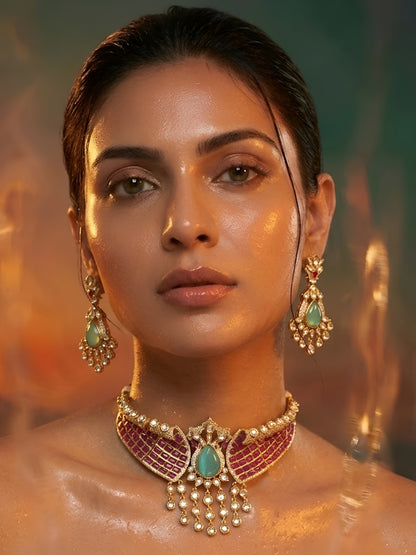 Royal pink Kundan choker necklace set with green teardrop stone, pearl danglers, and matching earrings in gold-plated finish.