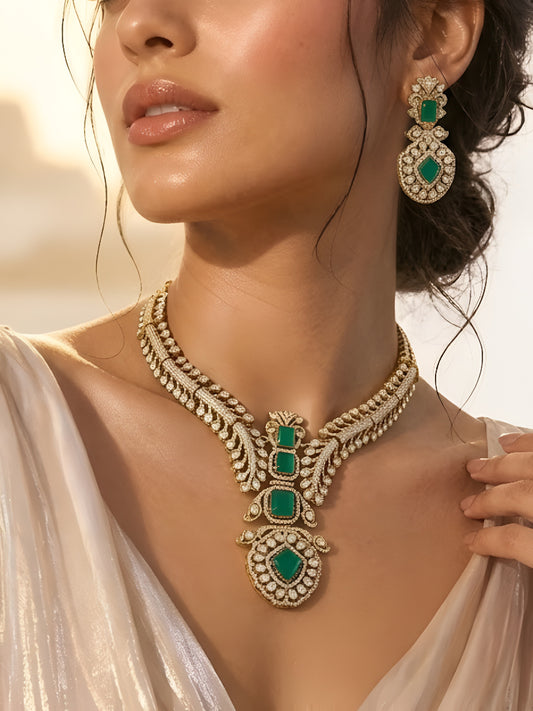Gold-plated American diamond necklace set with emerald green stones and matching earrings for women, perfect for bridal, wedding, festive, and party wear.