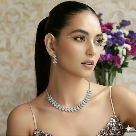 Silver necklace and matching earrings set with green and clear crystals displayed on a red velvet jewelry stand, perfect for weddings and formal events.