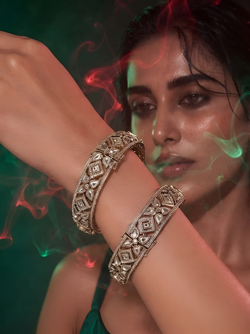 "Pair of gold-plated Kundan bangles with white stones in floral geometric design, traditional Indian bridal jewelry on white background"