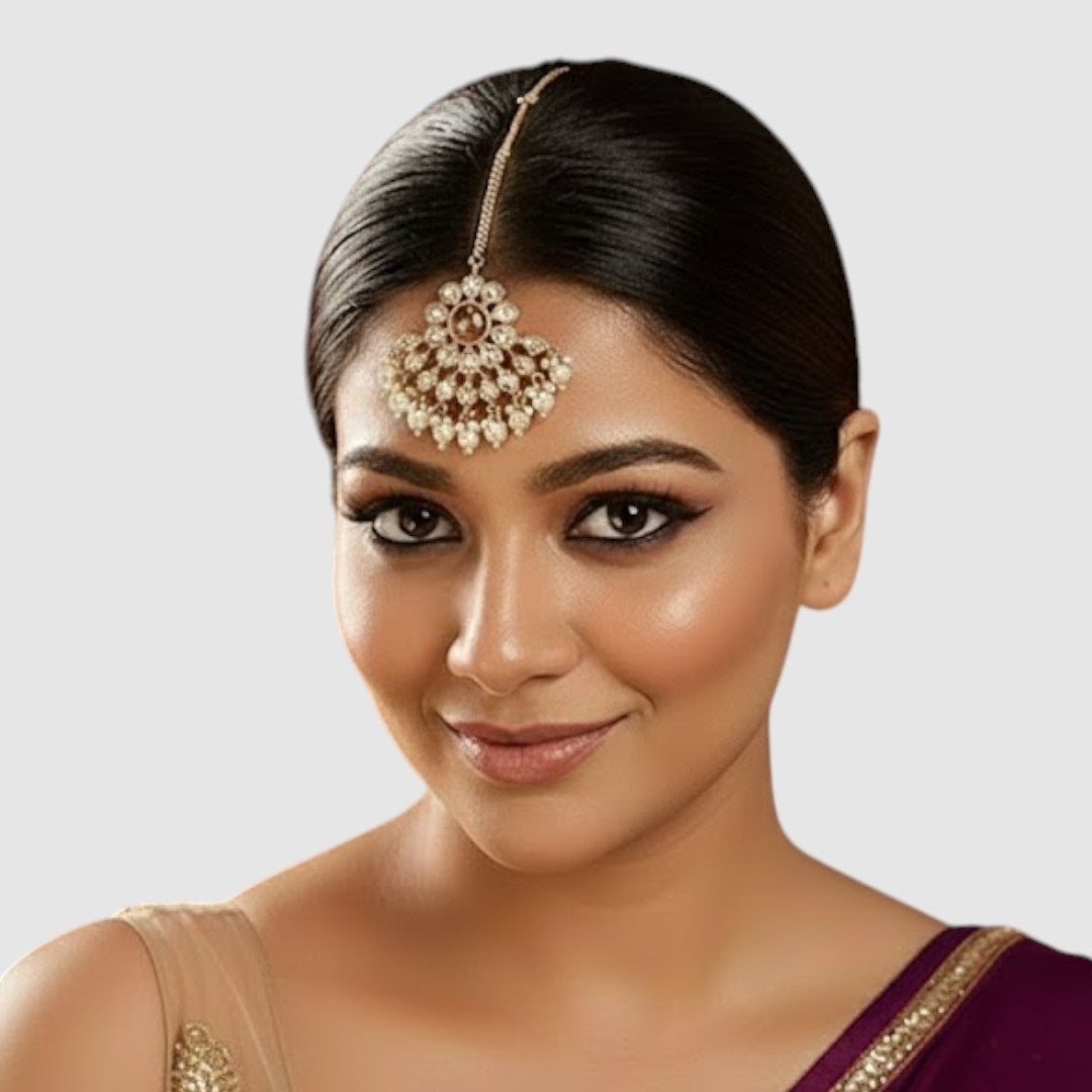 Gold-plated floral kundan maang tikka with pearl drops on a light background