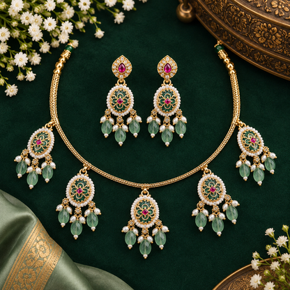 Gold plated mint green oval medallion necklace set with pink stones, green bead and pearl drops and matching earrings on a blue bust