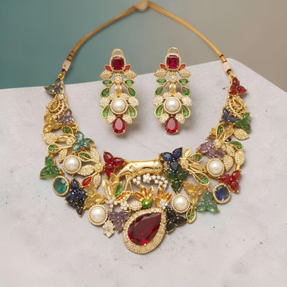 Gold plated multicolour designer necklace with ruby red teardrop centre stone, pearls and deer figure on a display bust