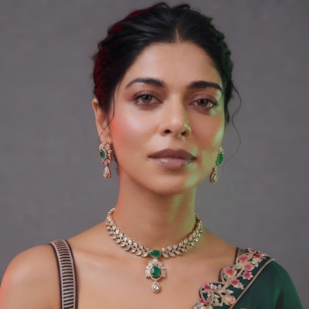 Woman wearing an emerald-green leaf-design kundan necklace set with pendant and matching drop earrings