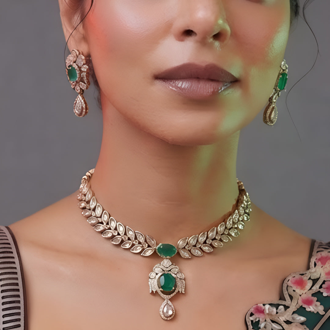 Woman wearing an emerald-green leaf-design kundan necklace set with pendant and matching drop earrings