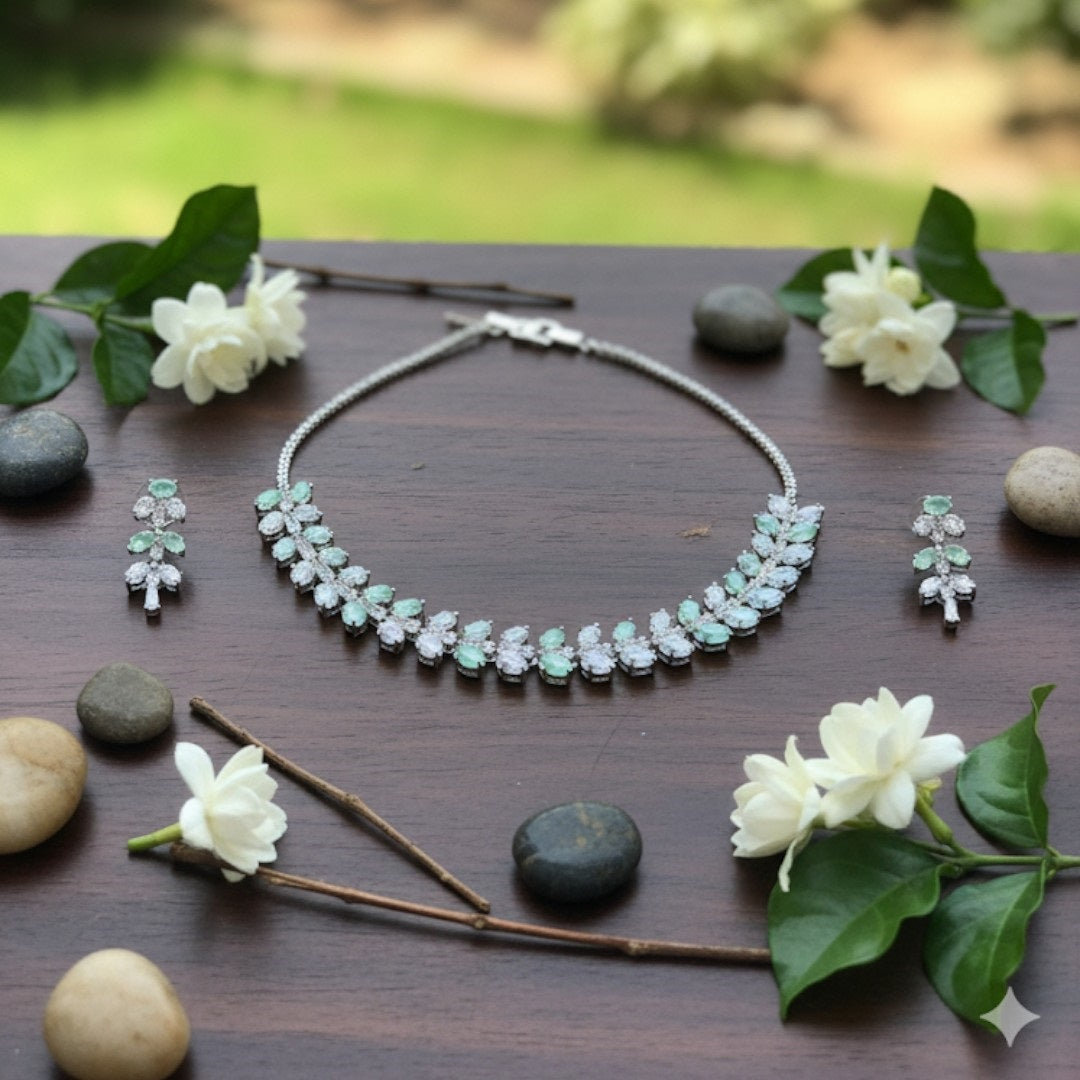 Silver necklace and matching earrings set with green and clear crystals displayed on a red velvet jewelry stand, perfect for weddings and formal events.