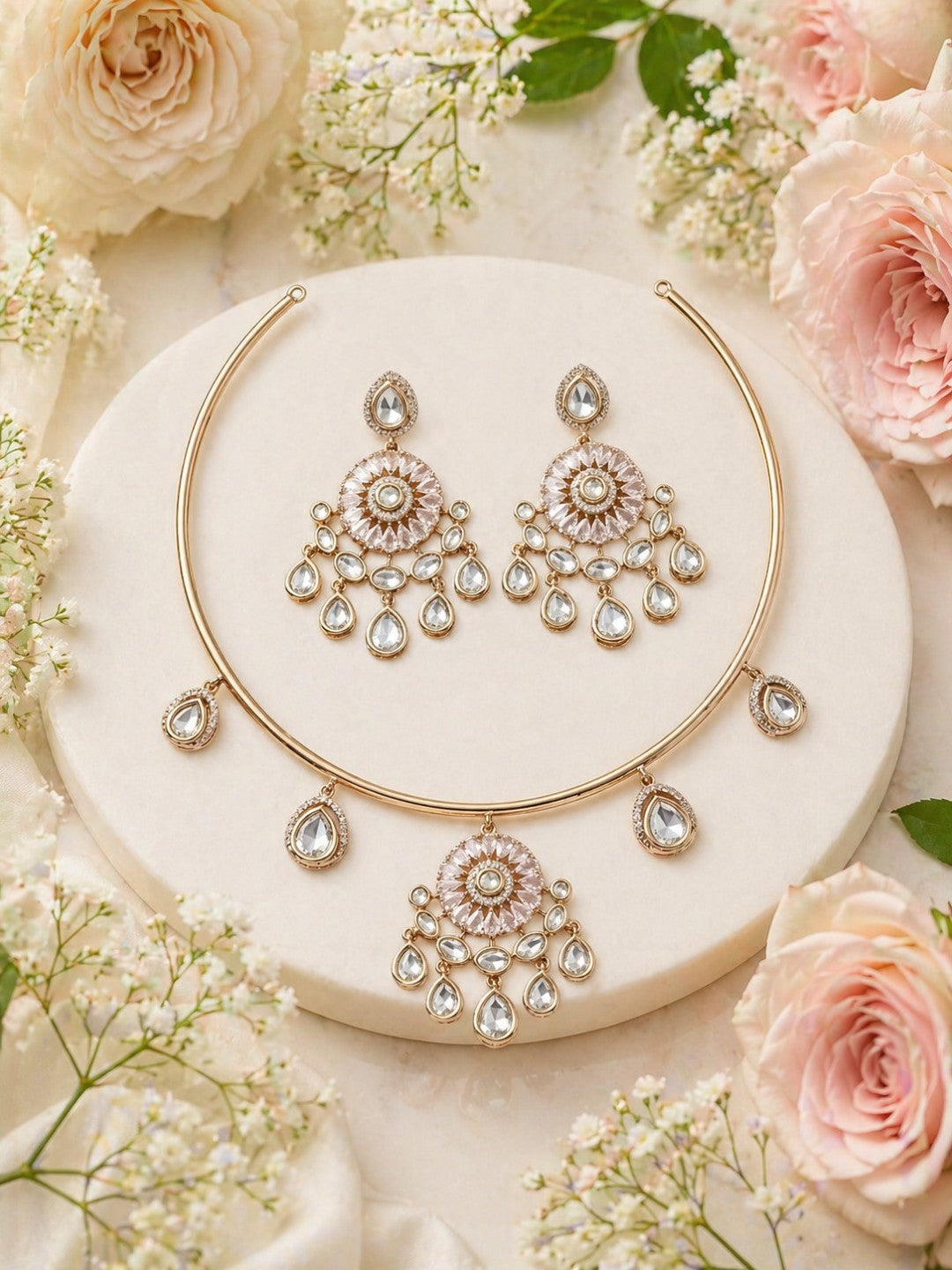 Rose gold plated kundan choker necklace set with crystal teardrop danglers and matching earrings displayed on elegant marble background