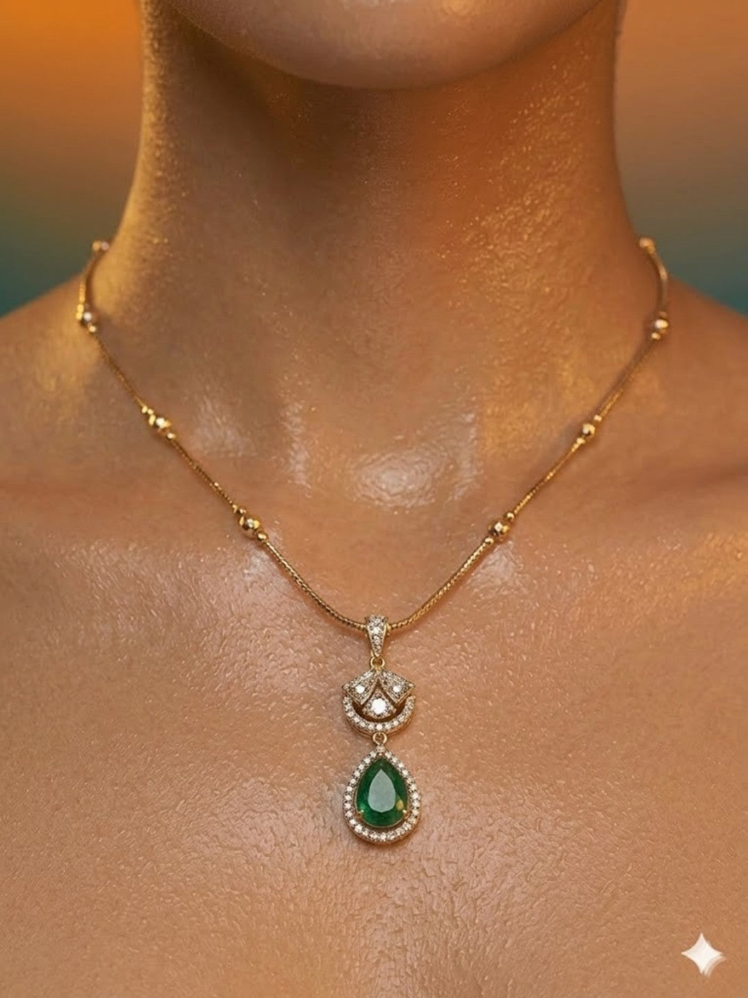 Gold-plated necklace set featuring emerald green teardrop pendant and matching drop earrings embellished with American diamonds.