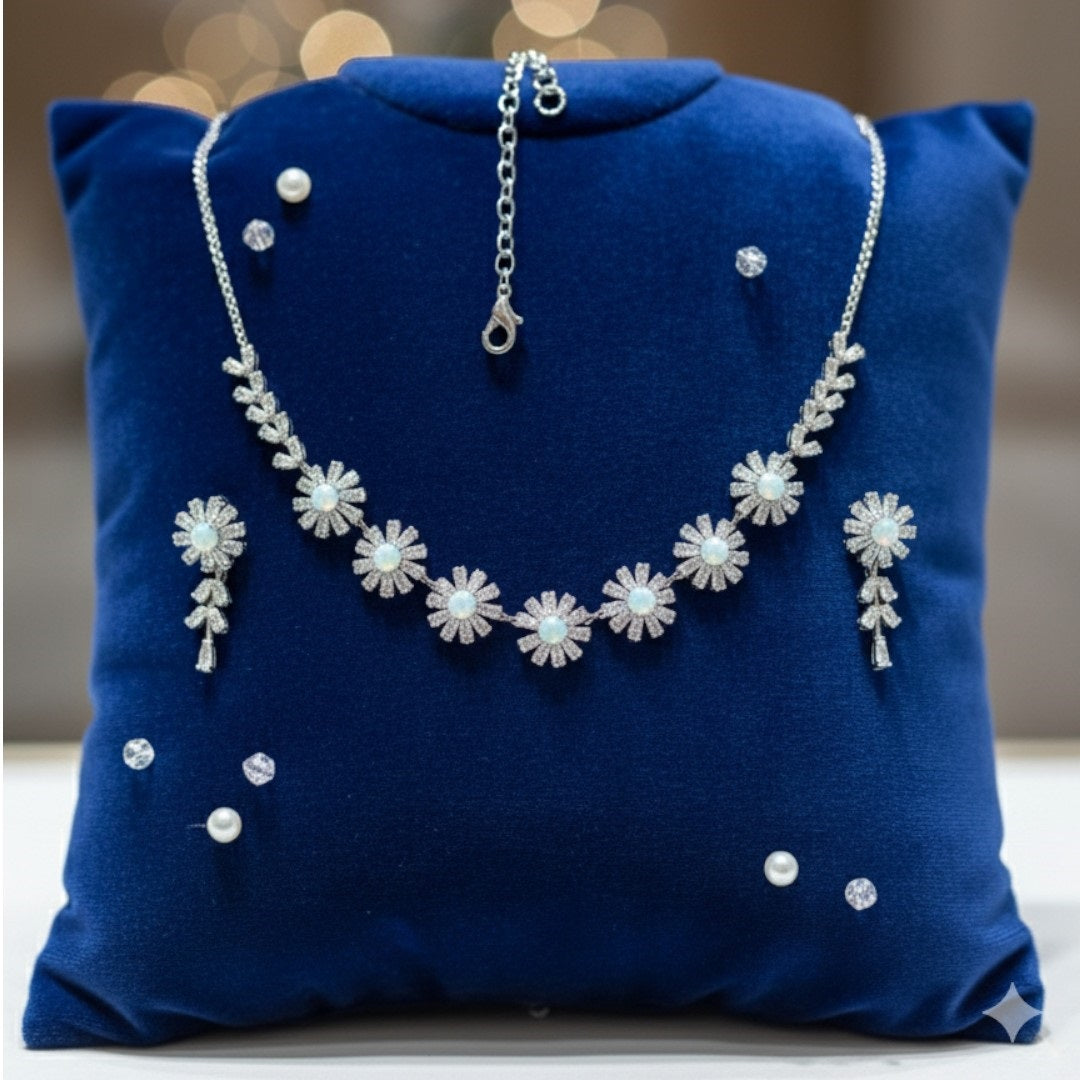 Elegant floral necklace and earrings set with green gemstone and sparkling American diamonds on red display stand