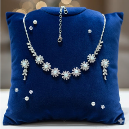 Elegant floral necklace and earrings set with green gemstone and sparkling American diamonds on red display stand
