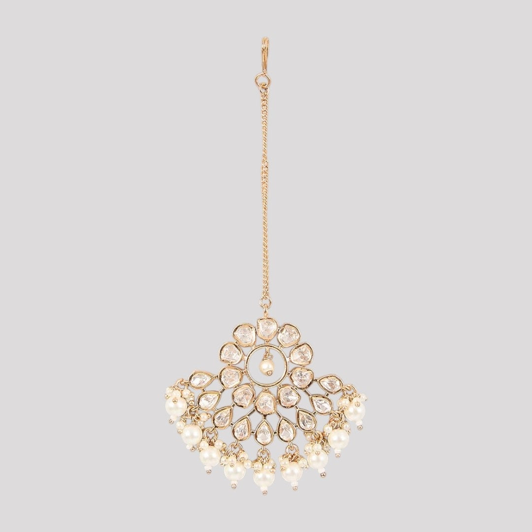 Gold-plated floral kundan maang tikka with pearl drops on a light background