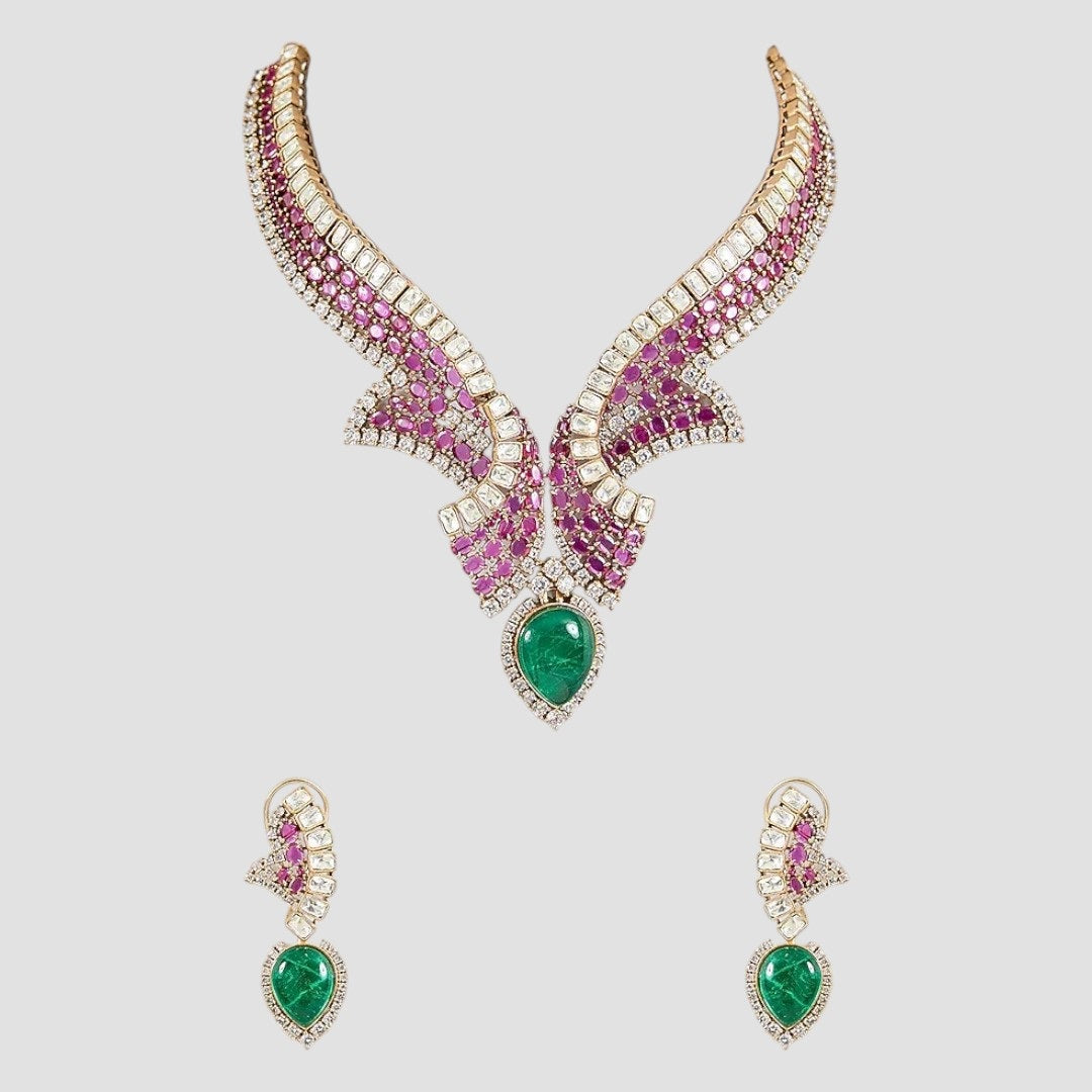 "Gold-plated designer necklace set with ruby stones, white crystals, and emerald teardrop centerpiece, paired with matching earrings"