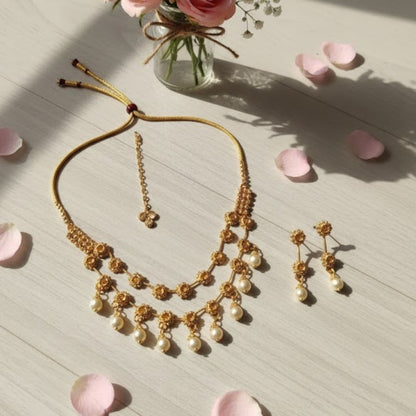 Traditional gold-plated necklace set with floral motifs and matching earrings displayed on red stand