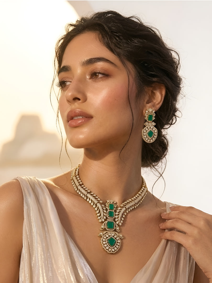Gold-plated American diamond necklace set with emerald green stones and matching earrings for women, perfect for bridal, wedding, festive, and party wear.