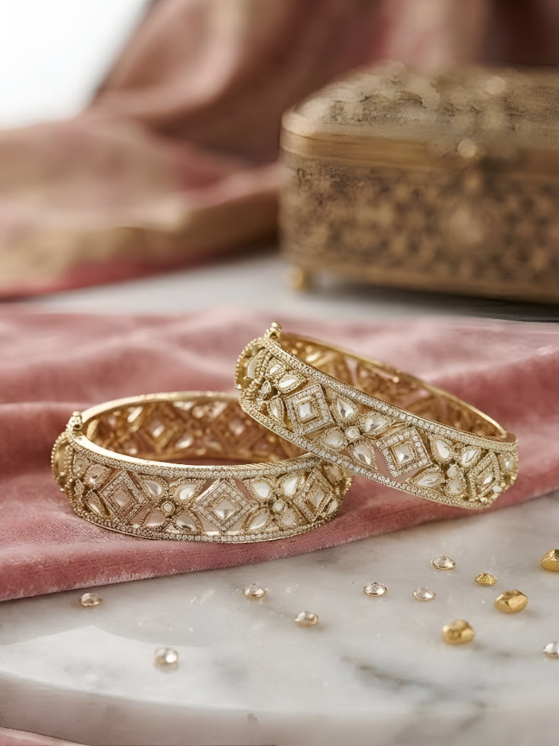 "Pair of gold-plated Kundan bangles with white stones in floral geometric design, traditional Indian bridal jewelry on white background"
