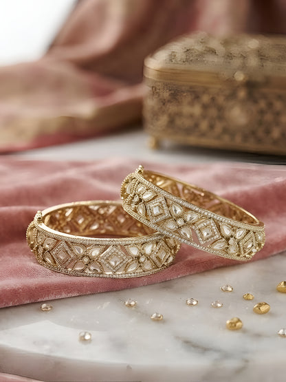 "Pair of gold-plated Kundan bangles with white stones in floral geometric design, traditional Indian bridal jewelry on white background"
