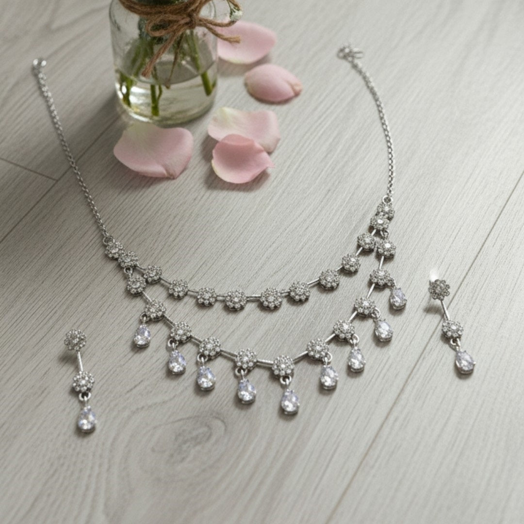 Elegant floral necklace set with matching earrings, silver-plated with crystal details.