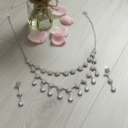 Elegant floral necklace set with matching earrings, silver-plated with crystal details.