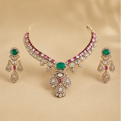 Gold-plated Kundan necklace set with green emerald-look center stone, pink ruby accents and matching American diamond earrings for bridal and wedding wear.