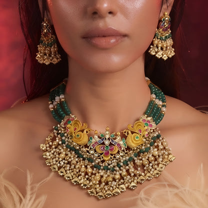 "Antique gold peacock motif necklace and earring set with green beaded strands and pearl drops, traditional temple jewellery on maroon backdrop"