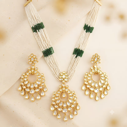 Multi-strand white pearl necklace with green bead bands and gold kundan chandbali pendant on a display bust