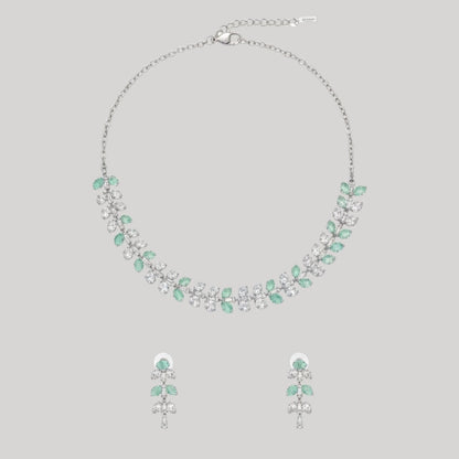 Silver necklace and matching earrings set with green and clear crystals displayed on a red velvet jewelry stand, perfect for weddings and formal events.