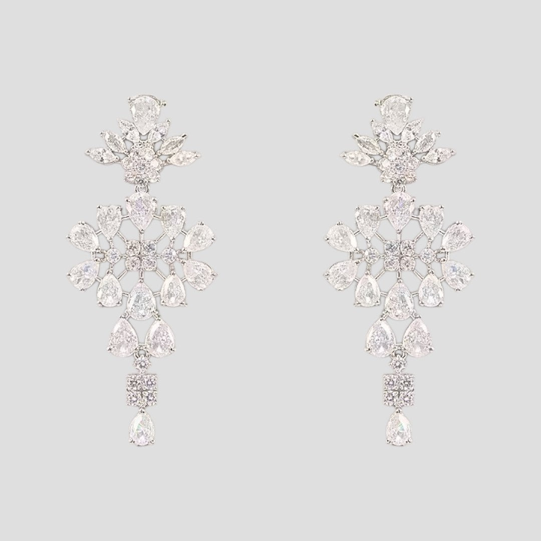 “Silver-tone crystal necklace with matching dangling earrings featuring floral and teardrop stone design.”