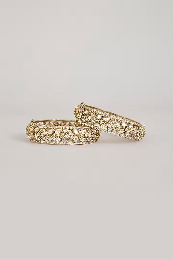 "Pair of gold-plated Kundan bangles with white stones in floral geometric design, traditional Indian bridal jewelry on white background"