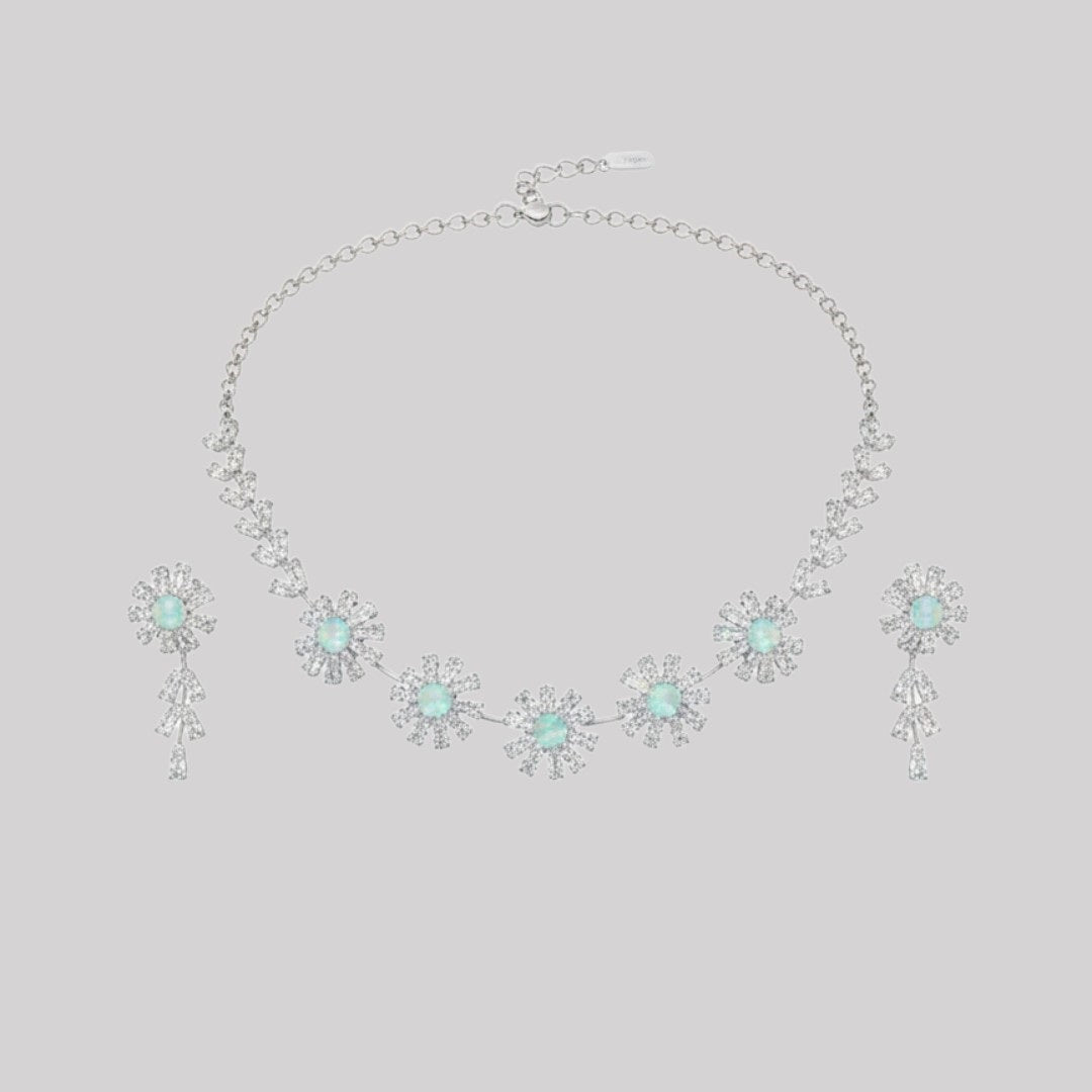 Elegant floral necklace and earrings set with green gemstone and sparkling American diamonds on red display stand