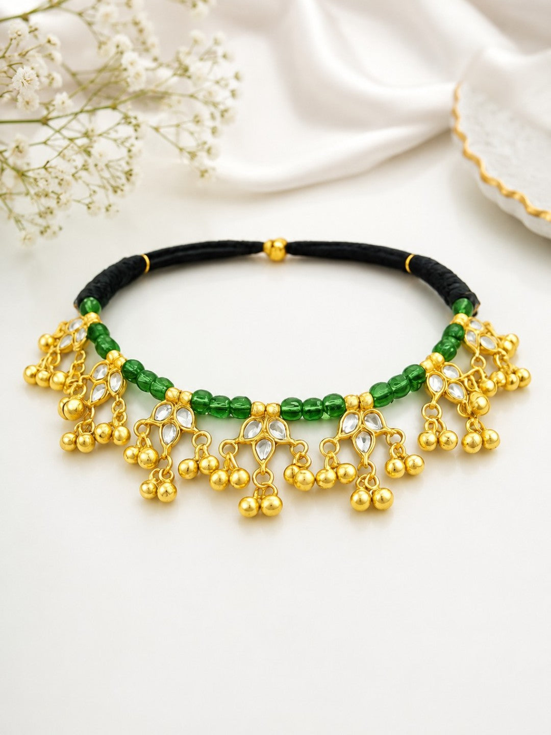 Traditional gold-plated Kundan choker necklace featuring green beads, black thread design, and decorative ghungroo danglers for women.