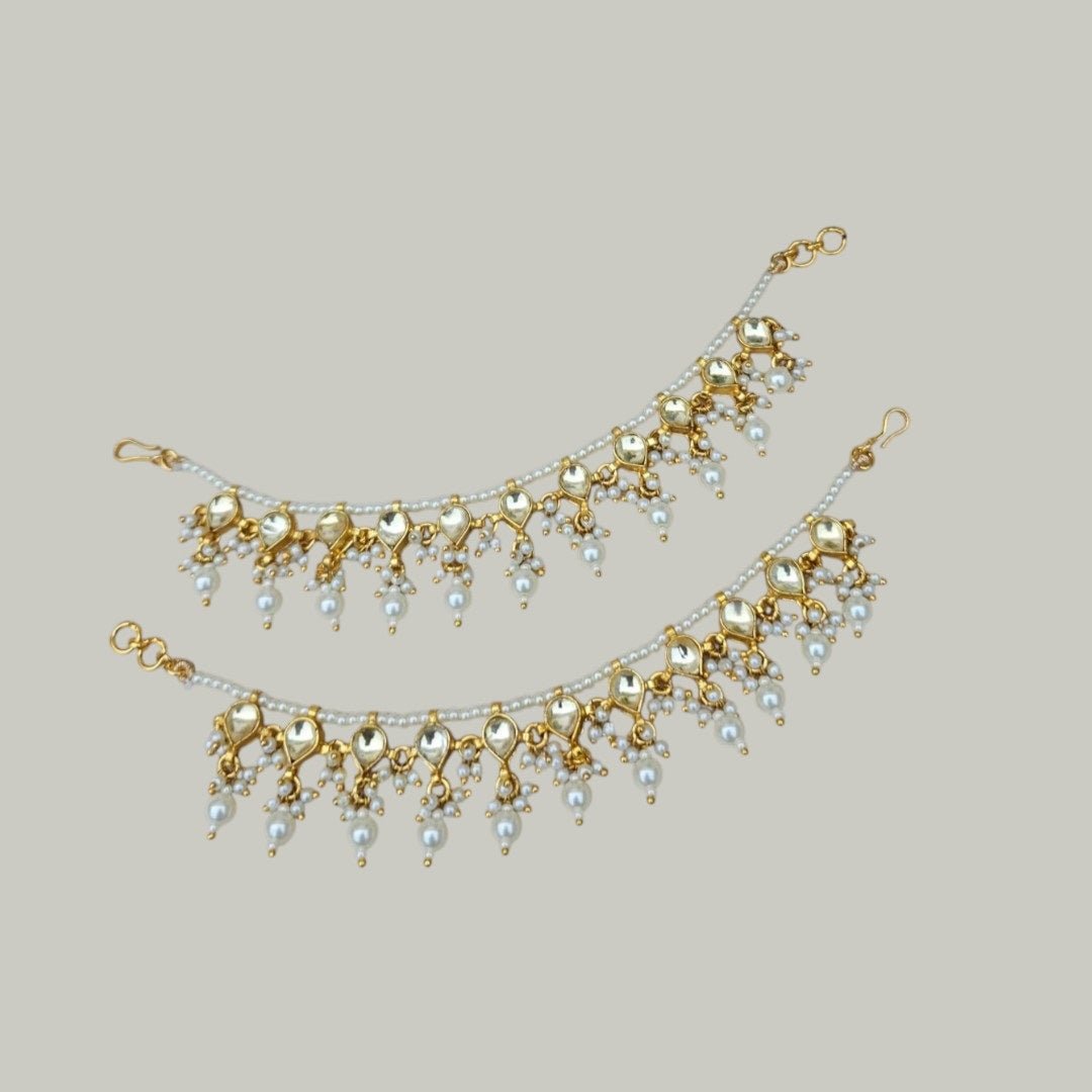 Classic Pearl & Golden Kundan Single Layer Kaan Chain - Auraa Trends - Kaan chain -  - Auraa Trends - Elegant golden Kundan and pearl single - layer Kaan Chain (Ear Chain) with heart - shaped motifs and dangling pearl drops, displayed on a beige fabric background with decorative flowers and seashell.