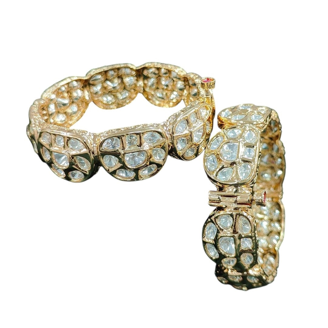 Gold plated traditional polki kundan bangles with petal-shaped panels, perfect for bridal and festive wear – displayed on a textured stone background with floral decor