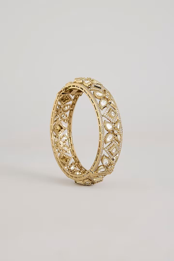 "Pair of gold-plated Kundan bangles with white stones in floral geometric design, traditional Indian bridal jewelry on white background"