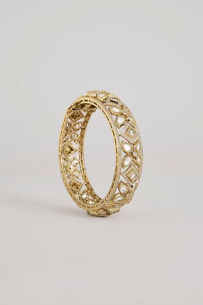"Pair of gold-plated Kundan bangles with white stones in floral geometric design, traditional Indian bridal jewelry on white background"