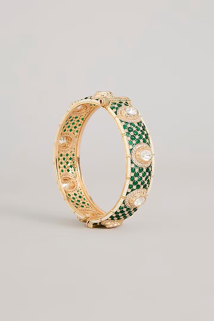 "Pair of gold-plated bangles with emerald green pave stones and Kundan detailing, traditional Indian jewelry