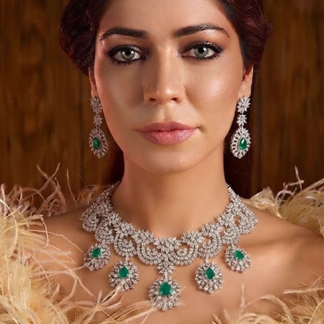 "Silver rhodium-plated bridal necklace set with white American diamonds and green emerald drop stones, paired with matching floral drop earrings"