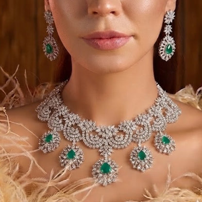 "Silver rhodium-plated bridal necklace set with white American diamonds and green emerald drop stones, paired with matching floral drop earrings"