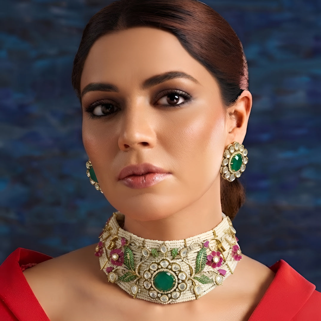 Designer gold-plated Kundan pearl choker necklace set with green centerpiece, floral pink stones, and matching stud earrings for women.