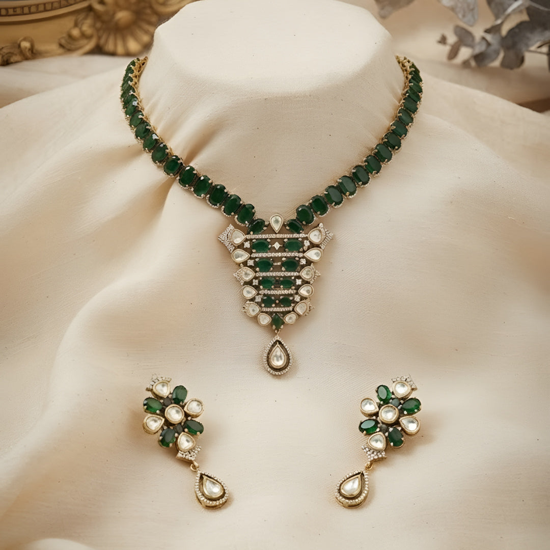 "Emerald green Kundan-style necklace and earring set with antique gold finish and white stone accents"
