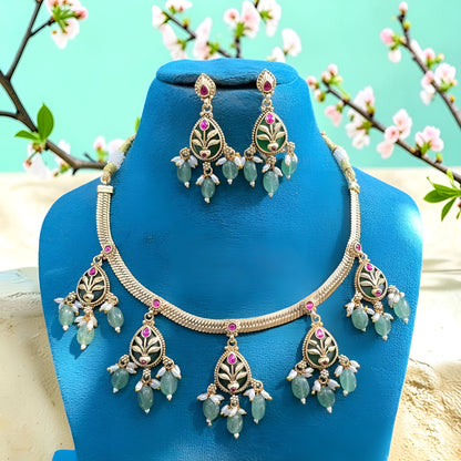Antique gold plated necklace set with dark green pear medallions, pink stones, mint green bead and pearl drops and matching earrings on a blue bust