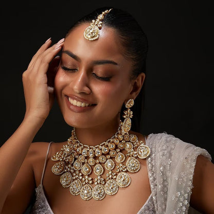 Gold-toned bridal kundan necklace set with pearl edging, maang tikka, and matching jhumka earrings