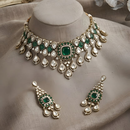 "Antique gold Kundan choker necklace with cushion-cut emerald center and polki teardrop drops, matching chandelier earrings"