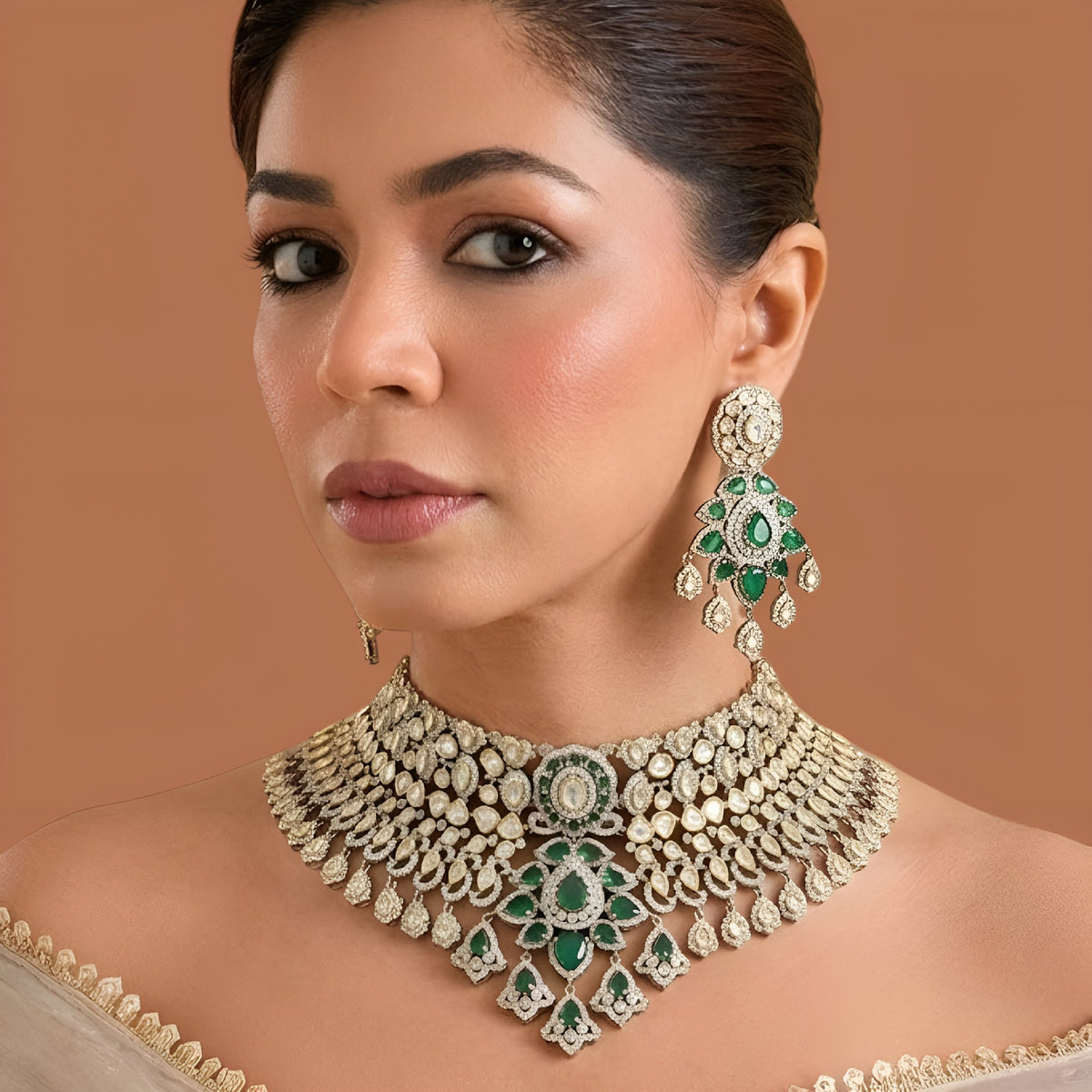 Gold-tone emerald green bridal choker necklace set with kundan-style stones, American diamond detailing, pear pendant cluster and chandelier earrings on dark green velvet