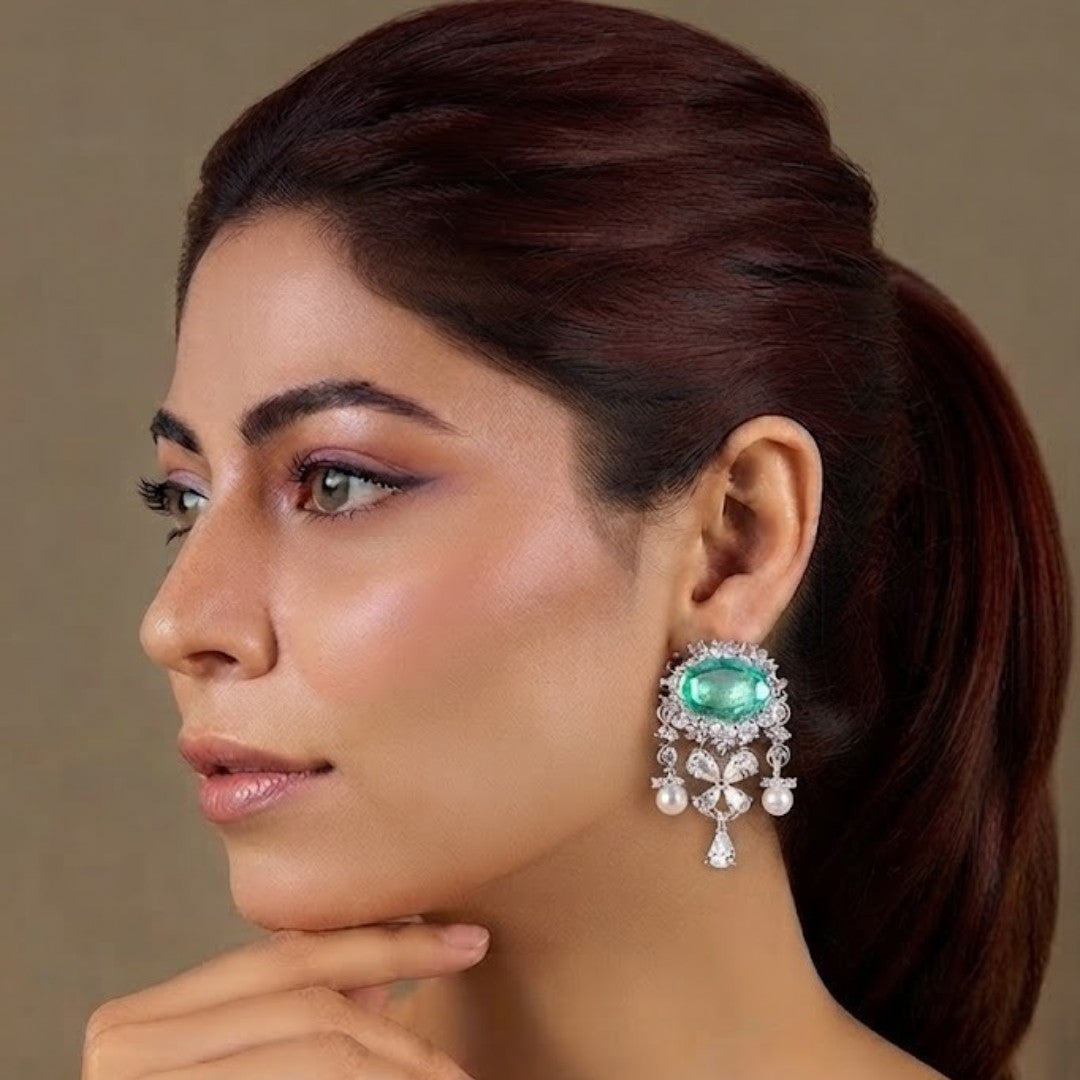 "Silver rhodium-plated drop earrings with oval emerald stone, diamond halo, clover-shaped white stones and pearl bead accents"
