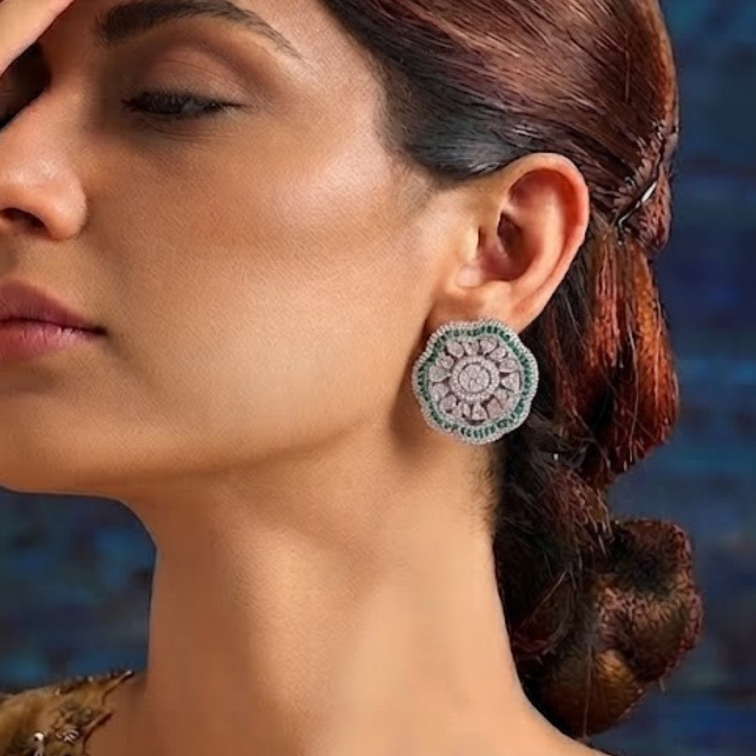 "Silver rhodium-plated floral stud earrings with white American diamonds and emerald green baguette stone halo"