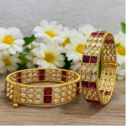Gold - Plated Designer Bangles with Ruby Red Square & Marquise White Stones - Auraa Trends - Bangles -  - Auraa Trends - Gold - plated ethnic bangles featuring marquise white stones and bold ruby red square stones, placed on a wooden surface with white daisies in the background – ideal for bridal and festive wear.