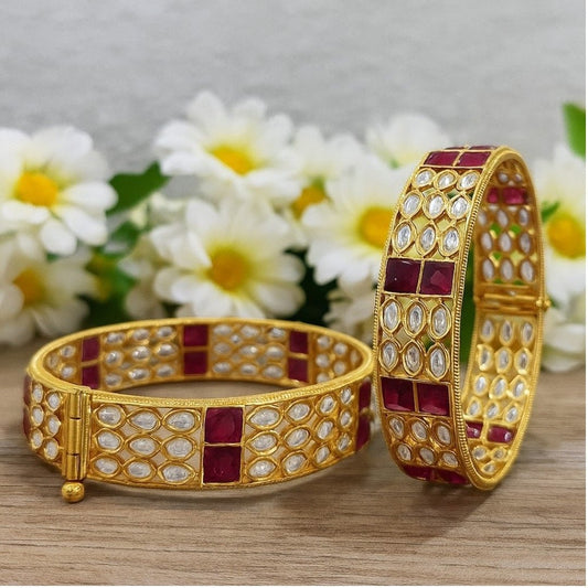 Gold - Plated Designer Bangles with Ruby Red Square & Marquise White Stones - Auraa Trends - Bangles -  - Auraa Trends - Gold - plated ethnic bangles featuring marquise white stones and bold ruby red square stones, placed on a wooden surface with white daisies in the background – ideal for bridal and festive wear.