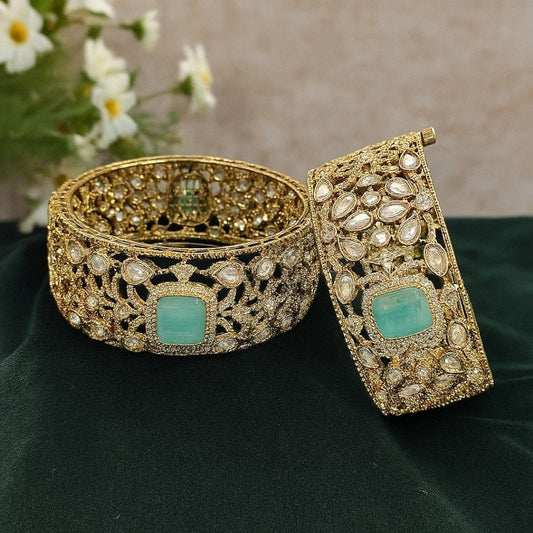 Gold - Plated Designer Broad Bangles with Mint Green Stone & Kundan Detailing - Auraa Trends - Bangles -  - Auraa Trends - “Set of two gold - plated broad bangles with pastel mint green stones and intricate kundan - style design, displayed on dark green velvet fabric.”