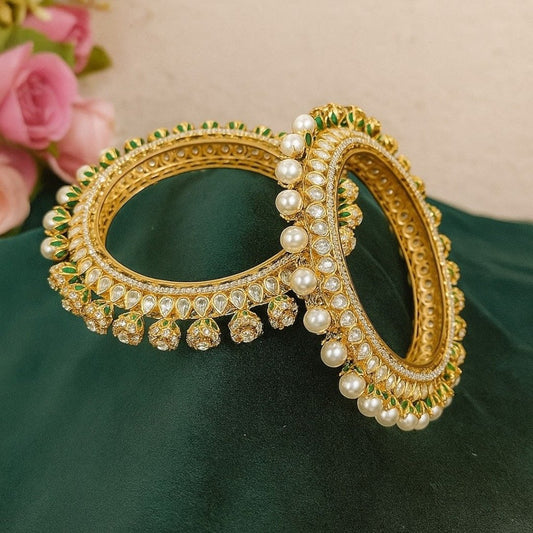 Gold - Plated Pearl & Kundan Bangles with Green Enamel Detailing - Auraa Trends - Bangles -  - Auraa Trends - Gold - plated bangles with kundan stones, pearl embellishments, and jhumka - style hanging drops, displayed on dark green velvet background