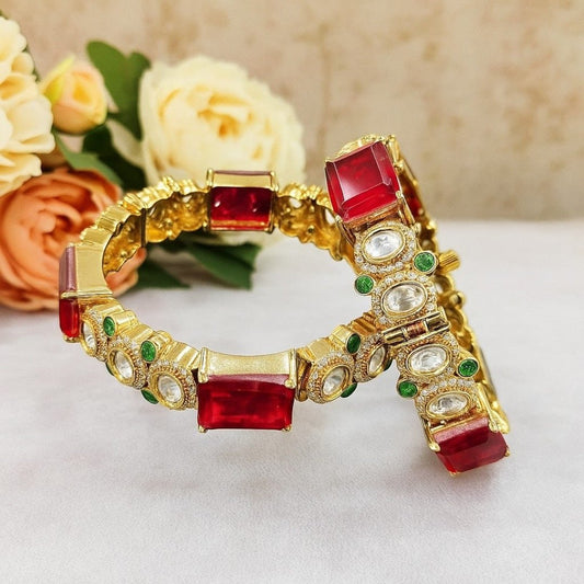 Gold - Plated Red Stone Bangles with Kundan & Green Detailing - Auraa Trends - Bangles -  - Auraa Trends - “Gold - plated traditional bangles with large red stones, kundan detailing, and green enamel accents – set of 2 displayed on white background with flowers.”